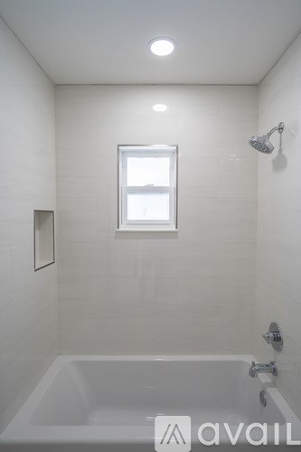A white bathroom with a tub and a window.