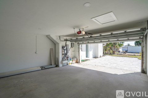A large empty garage with a white ceiling and a red fire alarm hanging from the ceiling.