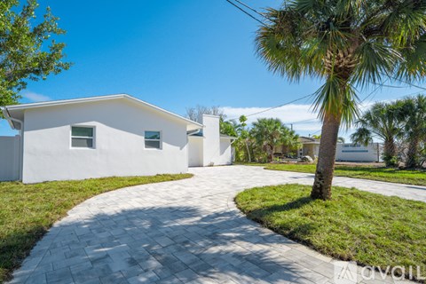 A white house with a palm tree in front.