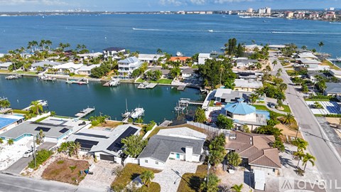 A bird's eye view of a coastal residential area with houses, boats, and a road.