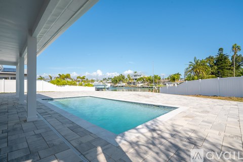 A pool surrounded by a white fence and a white building in the background.