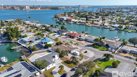 A bird's eye view of a residential area with a body of water and a bridge in the background.