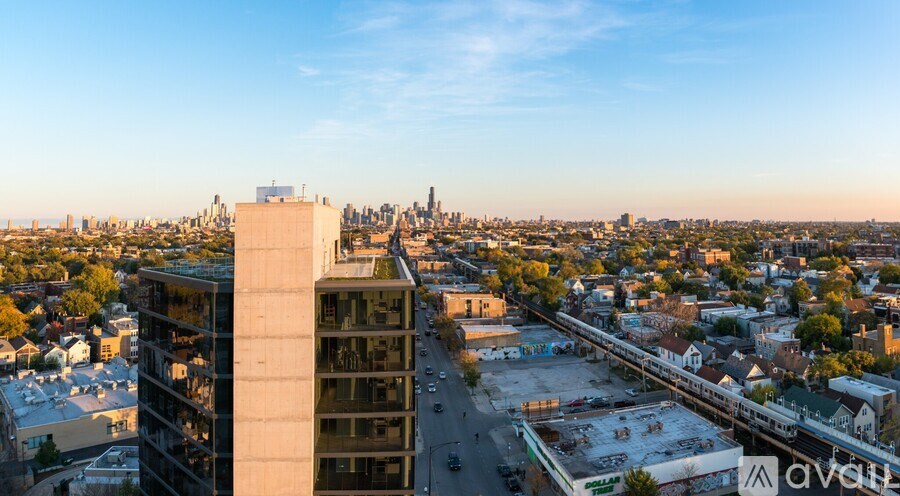 A cityscape with a prominent building in the foreground and a train track running through the middle.