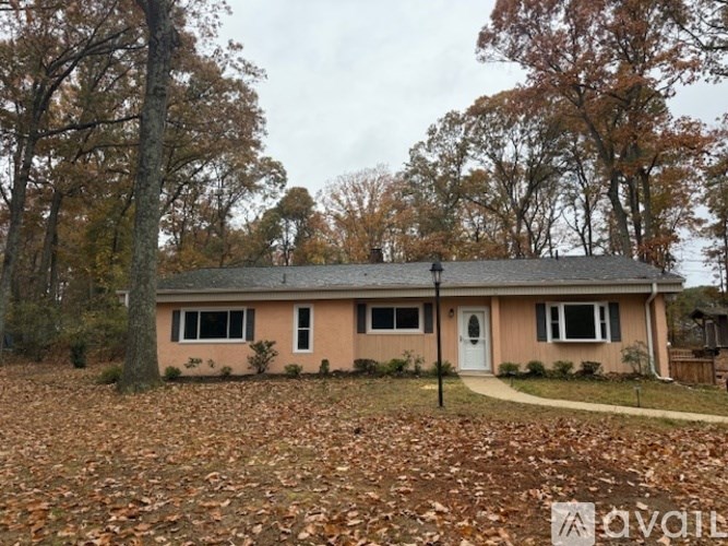 A house with a white door and windows is surrounded by trees with orange leaves.