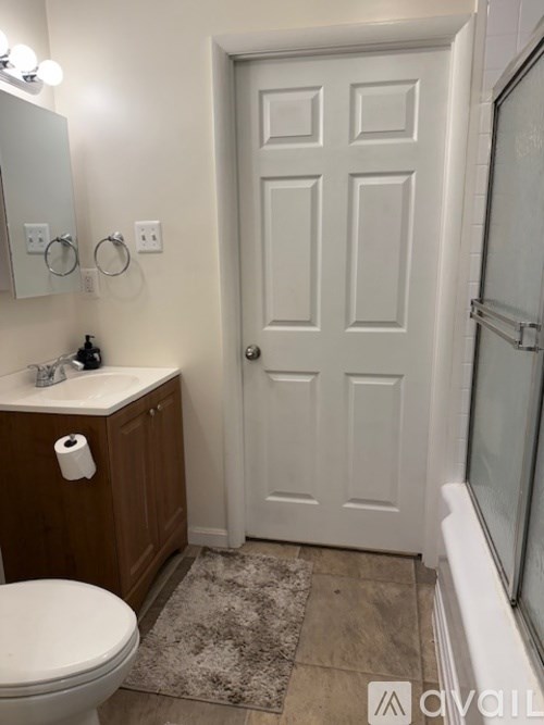 A white door is in a bathroom with a toilet and sink.