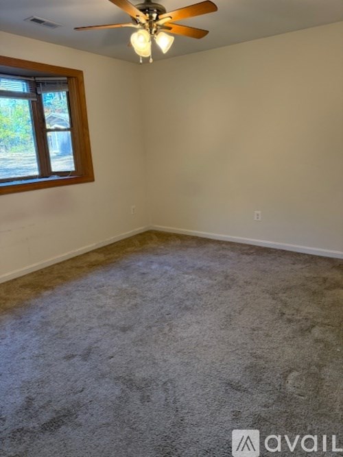 A room with a ceiling fan and a window.