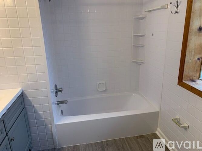 A white tiled bathroom with a bathtub and a cabinet.