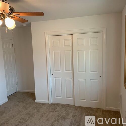 A room with a ceiling fan and a door.