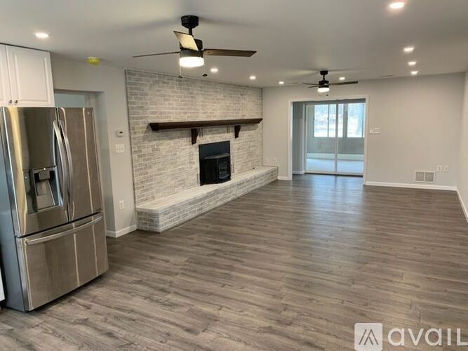 A spacious living room with a fireplace and a refrigerator.