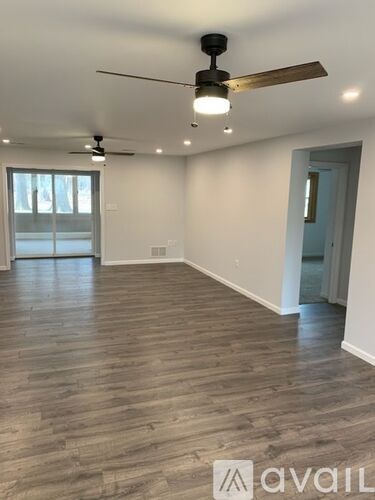 A spacious room with wooden flooring and a ceiling fan.