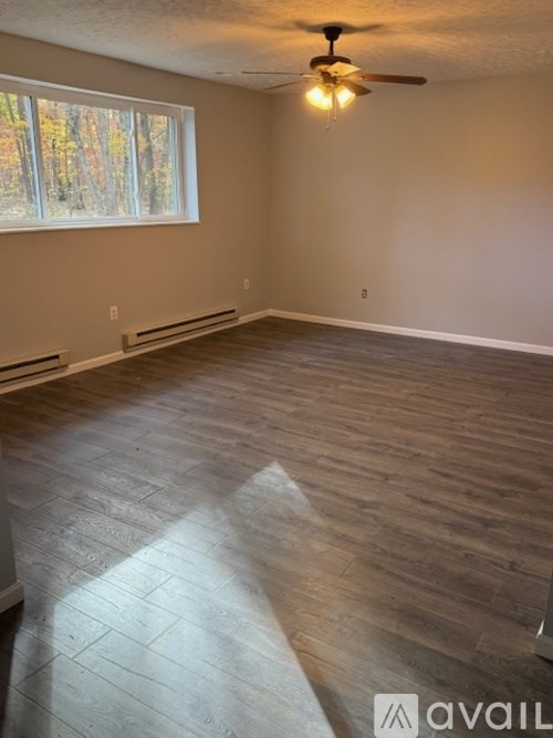 A room with a ceiling fan and wooden flooring.