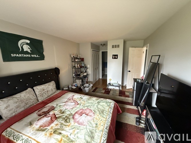 A Spartans banner hangs above a bed in a Spartans hotel room.