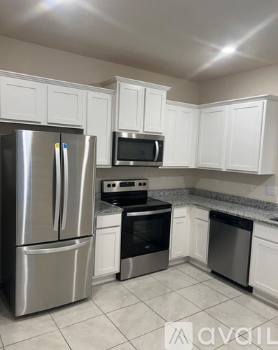 A kitchen with white cabinets and a stainless steel refrigerator.