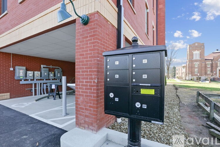 A black parking meter is installed on a sidewalk in front of a brick building.