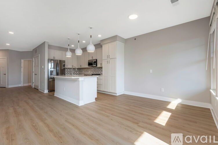 A spacious kitchen with wooden floors and a white island.