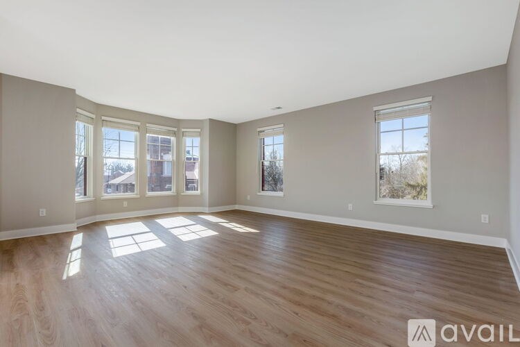 A spacious room with wooden flooring and large windows.
