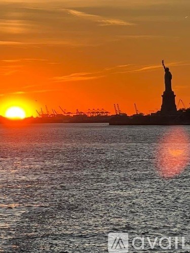 The Statue of Liberty stands tall against the sunset.