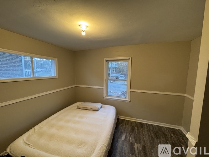 A bedroom with a bed, a window, and a wooden floor.