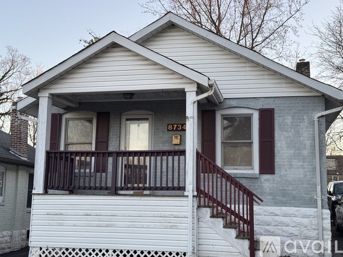 A small house with a porch and a red door.