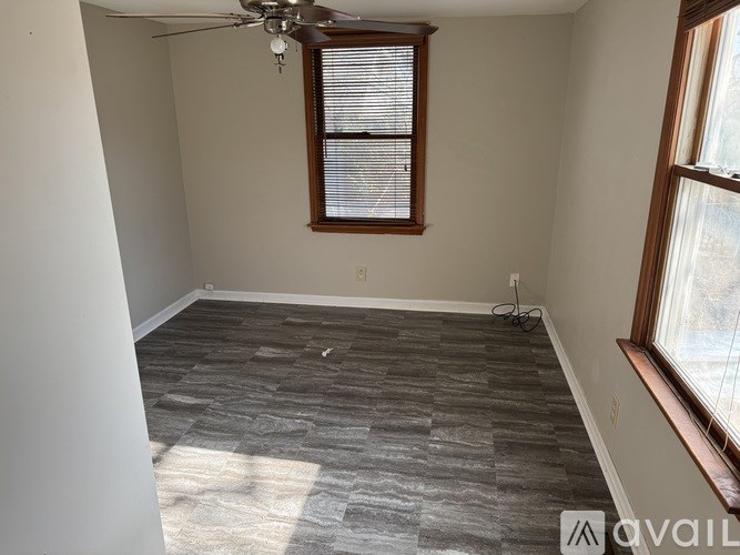 A room with a ceiling fan and a window with blinds.