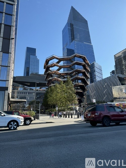 A city street with cars and a tall building with a unique design.