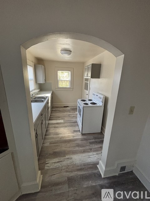 A kitchen with a white stove and wooden floors.