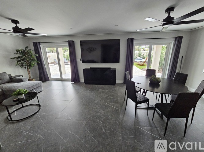 A living room with a grey floor and a black sofa.