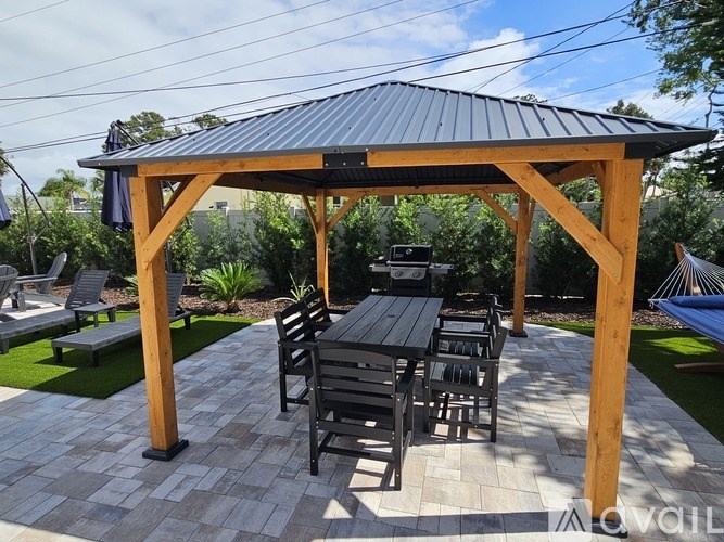 A wooden pergola with a black roof and a table set for four.