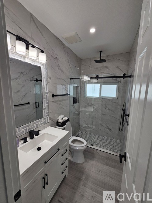 A bathroom with a marble wall and a walk-in shower.