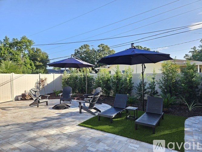 A patio with a table, chairs, and umbrellas.