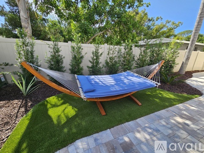 A blue hammock is strung between two wooden posts in a backyard.