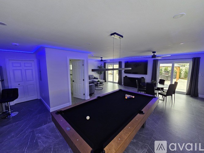 A pool table in a room with a television and chairs.