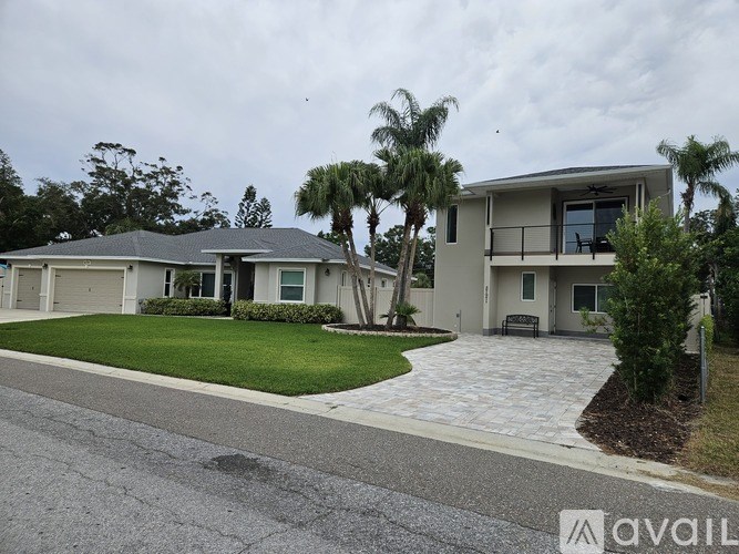 A house with a driveway and palm trees in front.