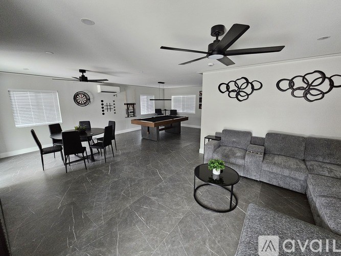 A living room with a grey couch, a black table, and a ceiling fan.