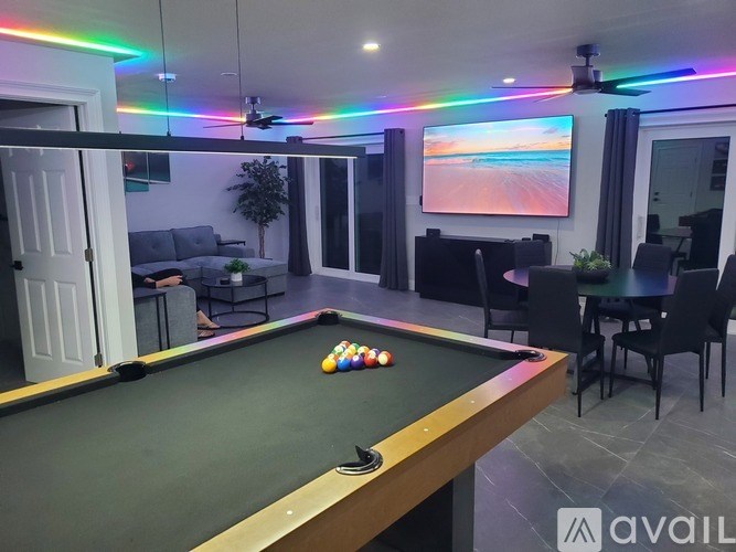 A room with a pool table and a ceiling fan with colorful lights.