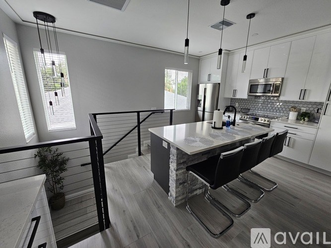 A modern kitchen with a large island and black chairs.