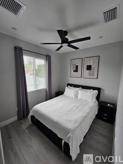 A bedroom with a bed, nightstand, and two pictures on the wall.