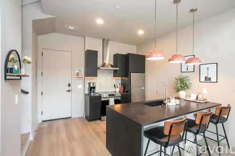 A modern kitchen with a black countertop and brown chairs.