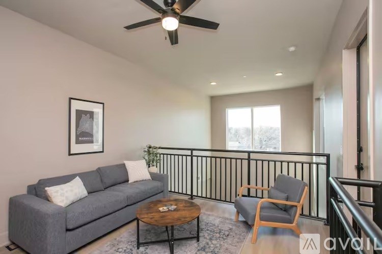 A living room with a grey couch, a coffee table, and a ceiling fan.