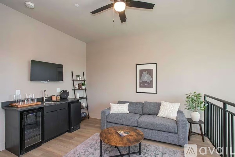A living room with a grey couch, a wooden coffee table, and a television on the wall.