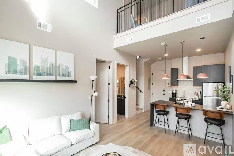 A modern living room with a white couch and a kitchen area in the background.