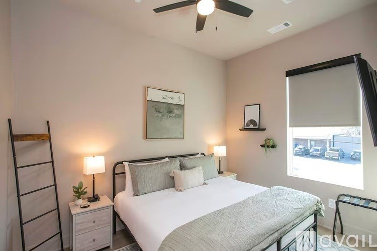 A bedroom with a bed, nightstand, and a painting on the wall.