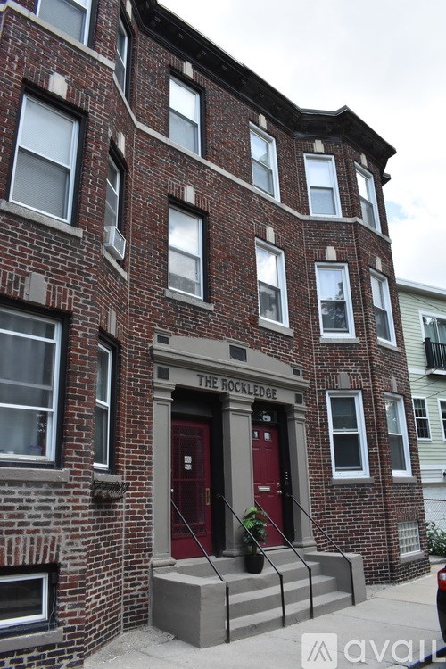 The front of a red brick building with a red door and windows.