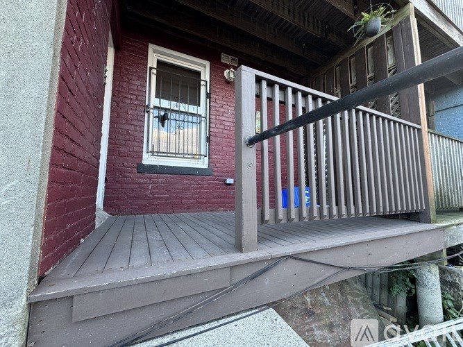 A red building with a wooden deck and a window with bars.