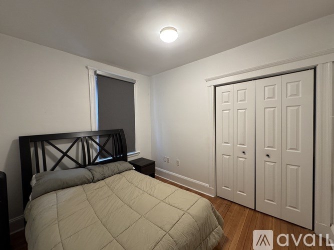 A bedroom with a bed, nightstand, and closet.