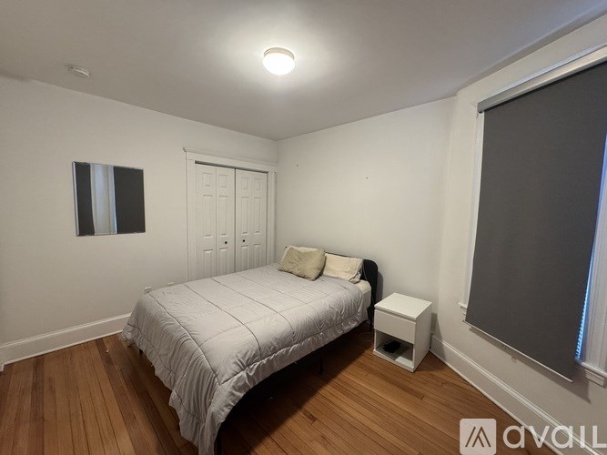 A bedroom with a bed, nightstand, and window.