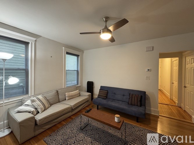 A living room with a couch, a fan, and a rug.