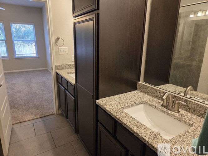 A bathroom with a granite countertop and a double sink.