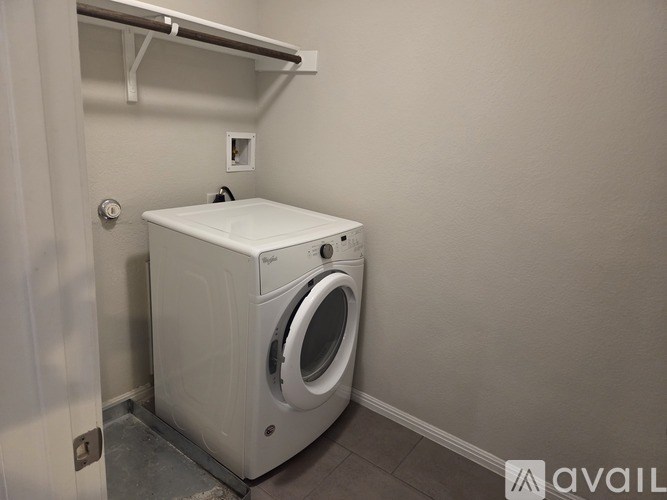 A white front loading washing machine in a small laundry room.