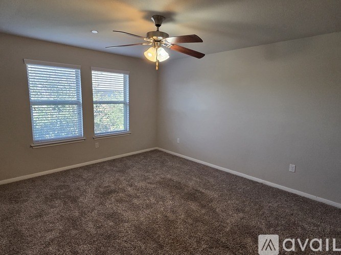 A room with a ceiling fan and carpeted floor.